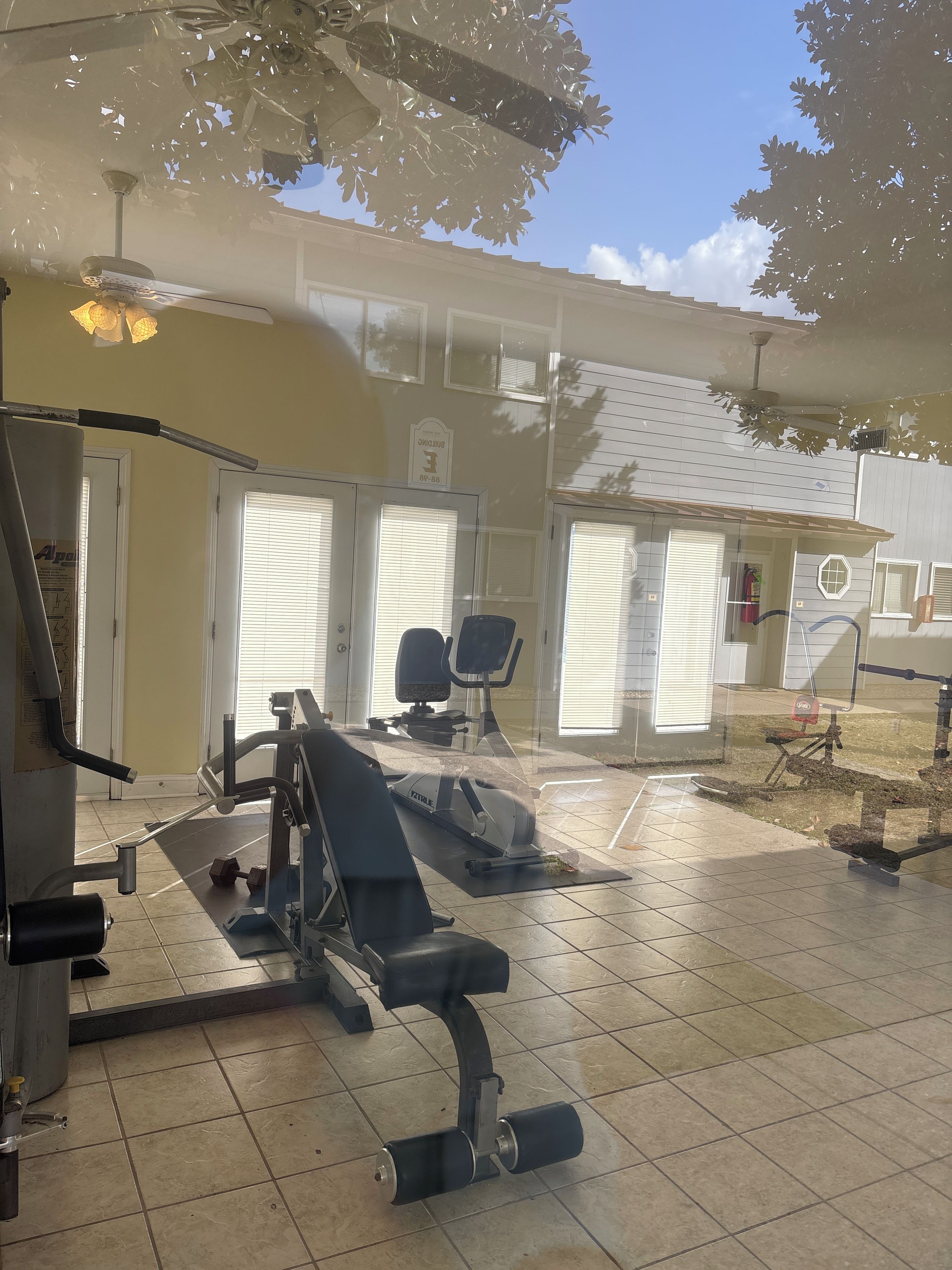 Une salle de sport équipée de matériel d’exercice, dotée d’un ventilateur de plafond et offrant une vue sur l’extérieur.