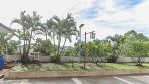 A landscaped garden with palm trees, a concrete pathway, and a street lamp. - Hotel O Mp Room (Depok)