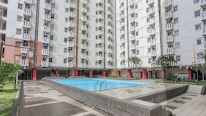 A residential building with multiple balconies, a swimming pool, and a tiled patio area. - Hotel O Mp Room (Depok)