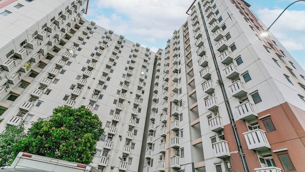 A high-rise residential building with multiple balconies and a clear sky. - Hotel O Mp Room (Depok)