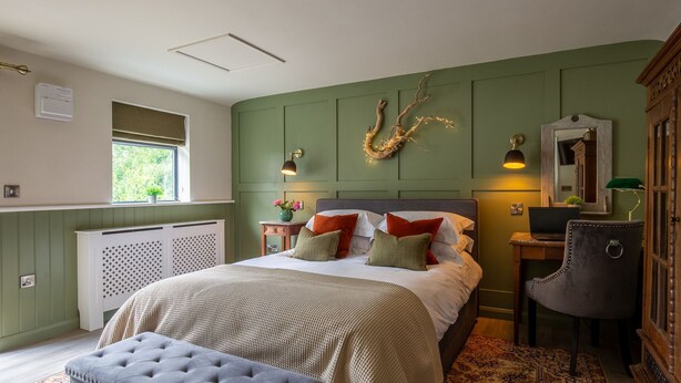 Une chambre à coucher comprenant un lit, une chaise, un bureau, un radiateur, une fenêtre et un miroir fixé au mur.