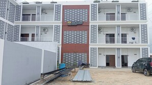 Un edificio de varios pisos con balcones y unidades de aire acondicionado, con un letrero que dice "The Cozy Rest Exclusive".