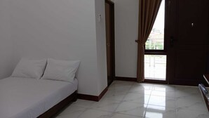 Un dormitorio con cama, una puerta y una ventana con cortinas.