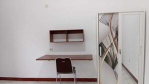 Una habitación con un escritorio de madera, una silla y una puerta de vidrio decorativa.