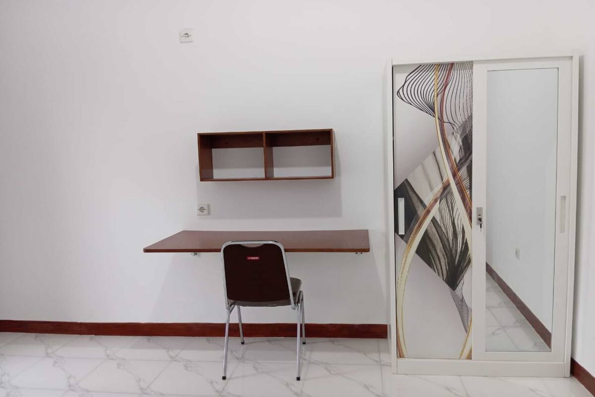 Una stanza con una scrivania in legno, una sedia e una porta decorativa in vetro.