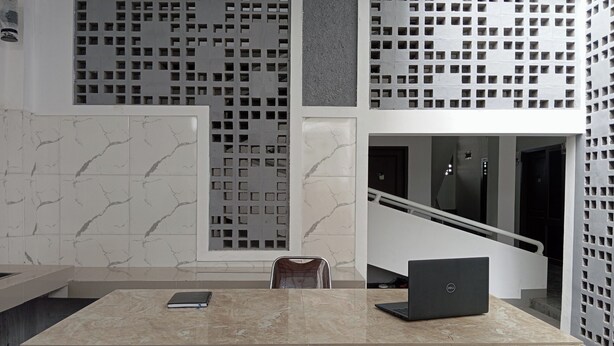 Un espacio de oficina moderno con una mesa con mosaicos de mármol, una computadora portátil y una silla.