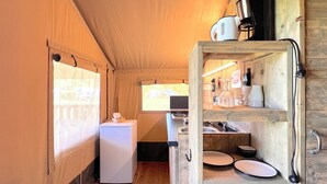Une cuisine de taille réduite, équipée d’un réfrigérateur, d’étagères en bois et d’une fenêtre.