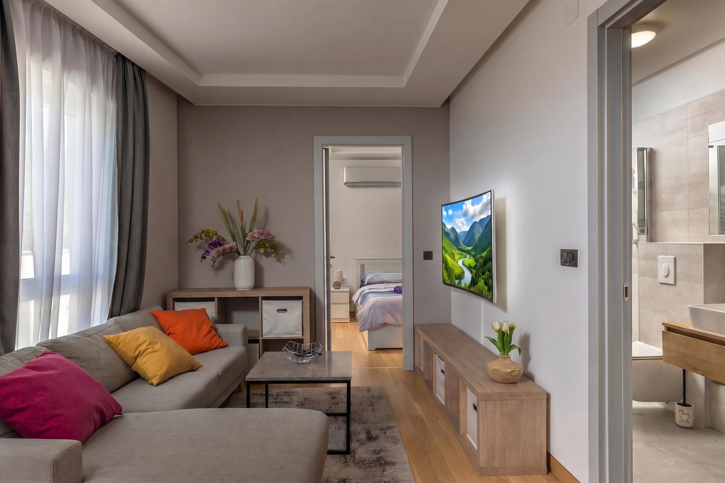 A modern living room with a sofa, coffee table, and a TV mounted on the wall.