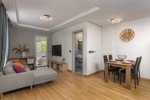 A modern living room with a sofa, TV, dining table, and chairs.