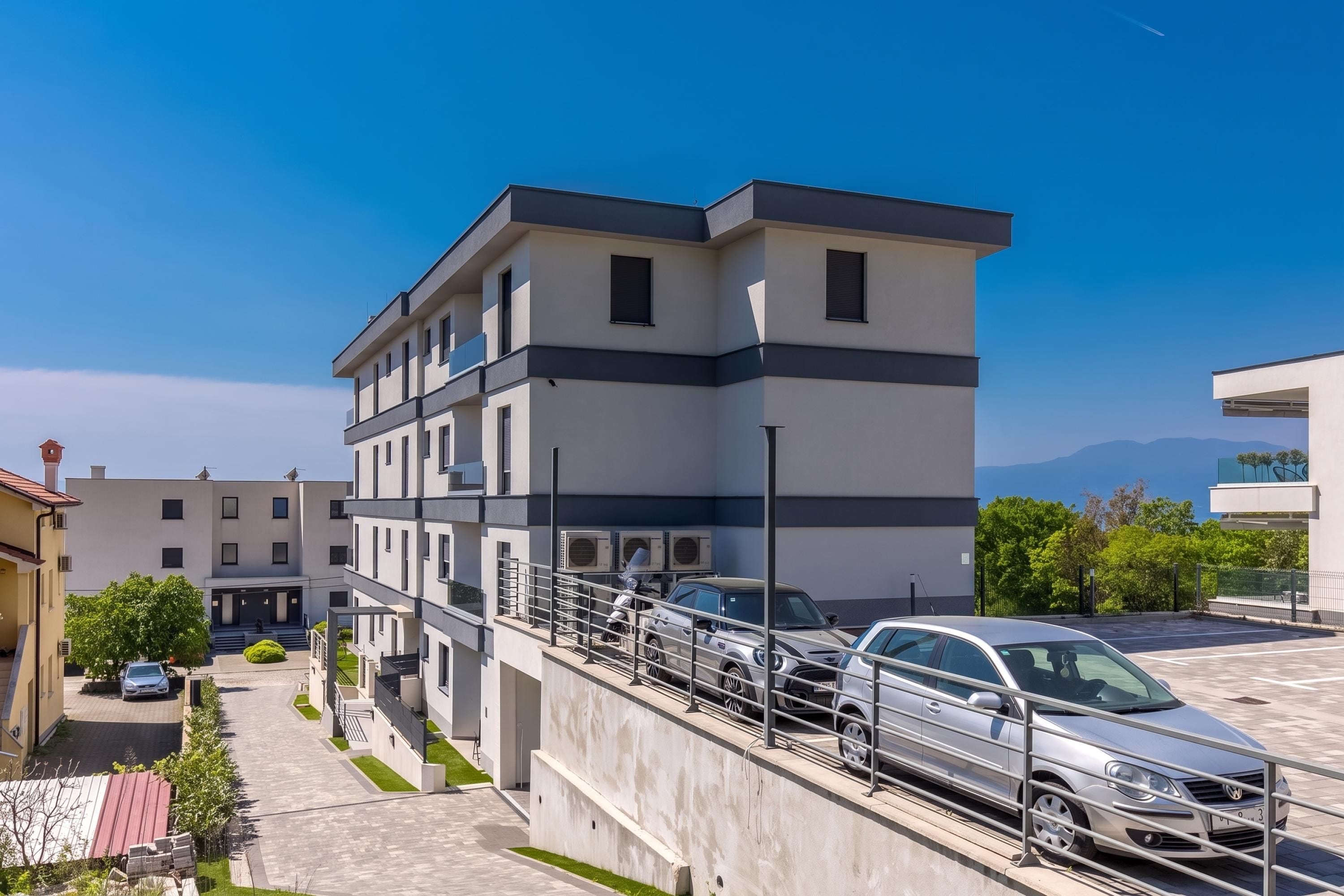 A modern multi-story building with a parking area and a clear view of the surrounding landscape.