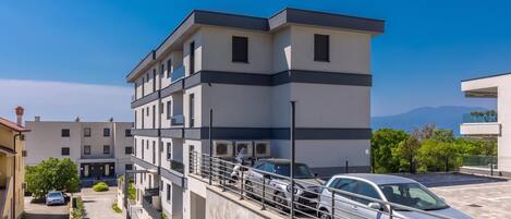 A modern multi-story building with a parking area and a clear view of the surrounding landscape.