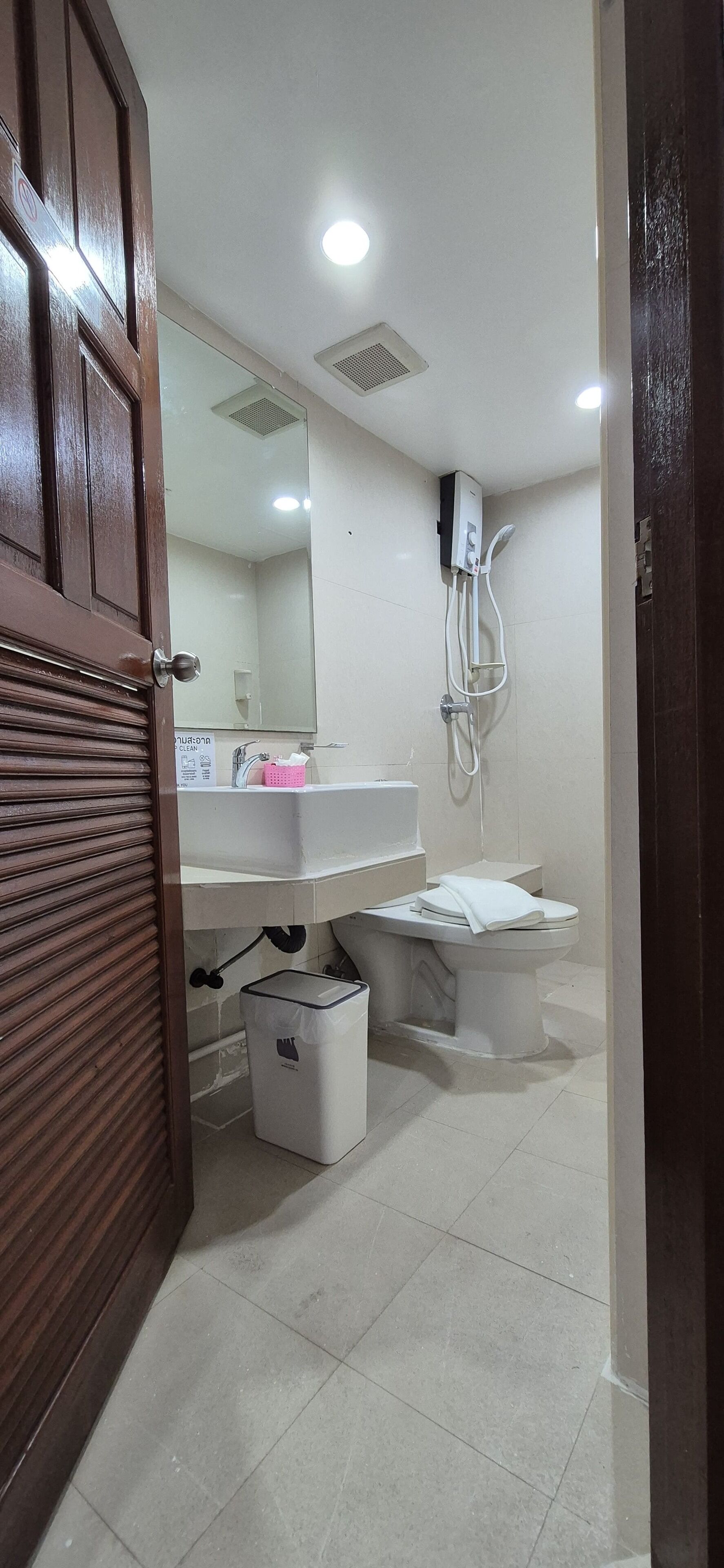 Une salle de bain comprenant des toilettes, un lavabo, un miroir et une douche.