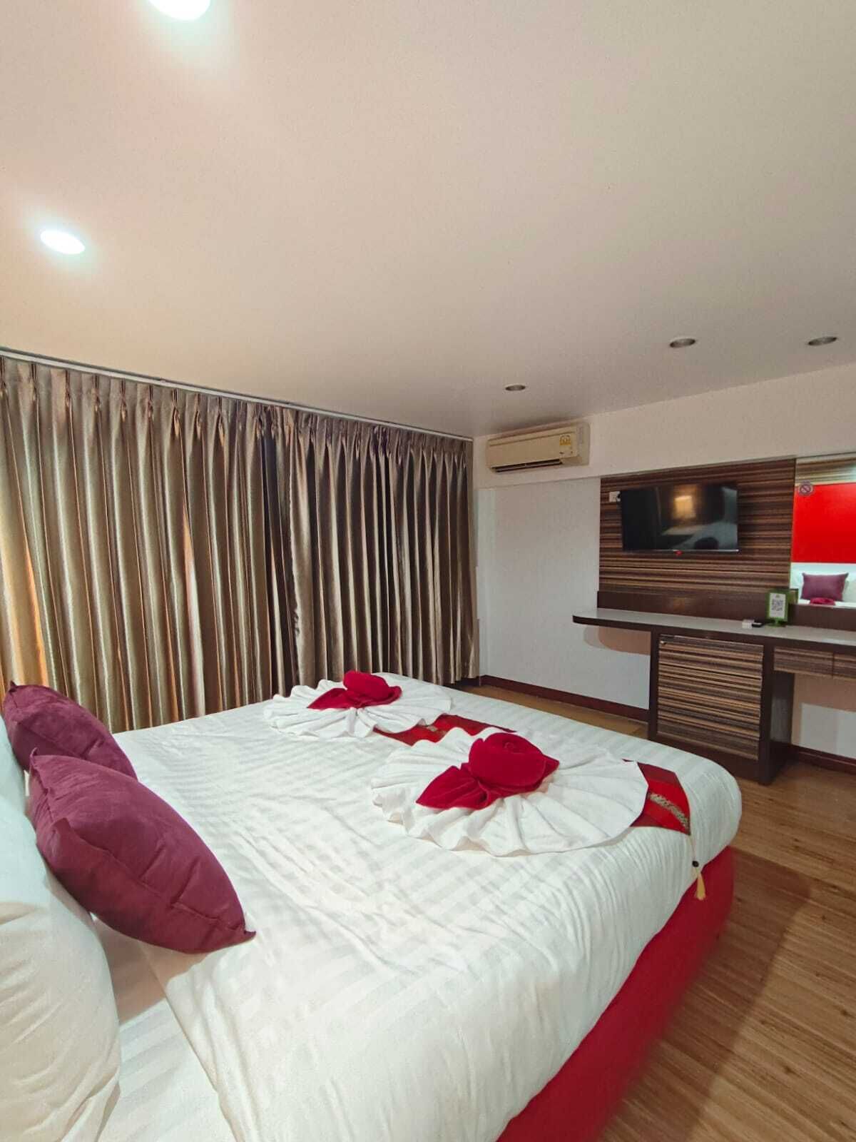 A modern hotel room with a large bed, a desk, and a TV.