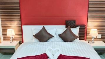 Una habitación de hotel con una cama grande, dos mesitas de noche y un cabecero rojo.