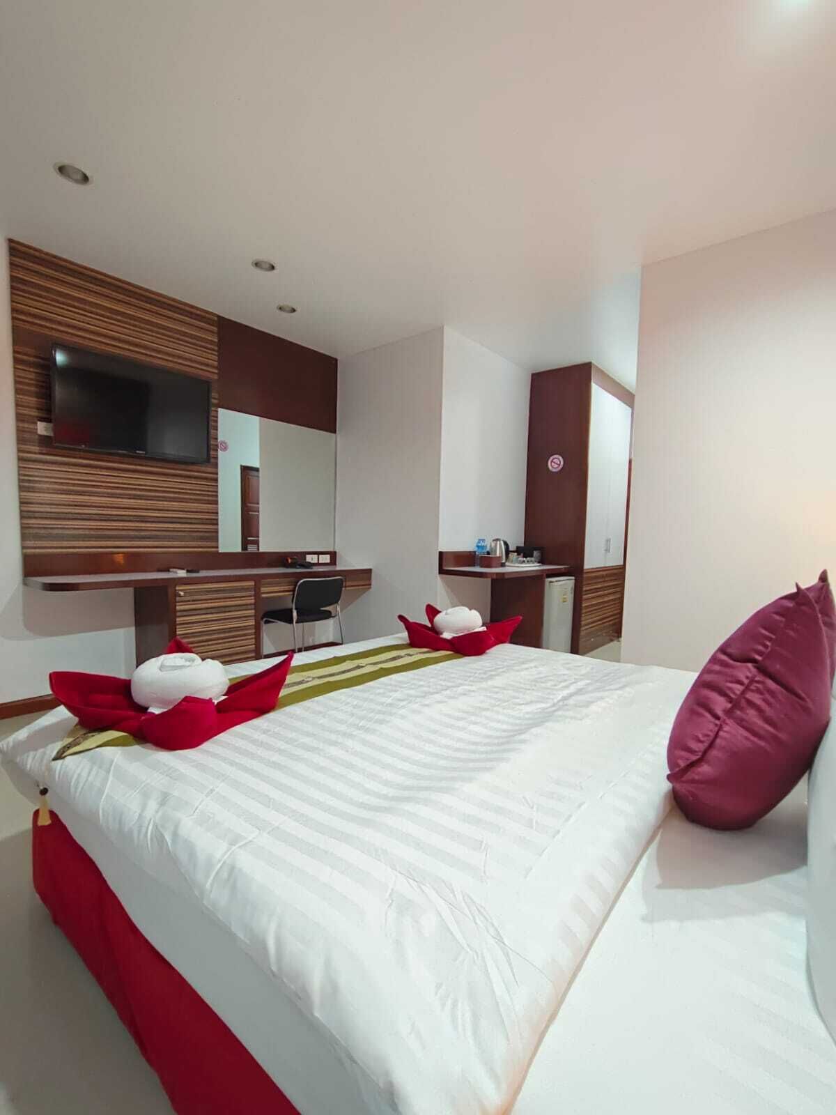 Een moderne hotelkamer met een groot bed, een bureau en een aan de muur bevestigde televisie.
