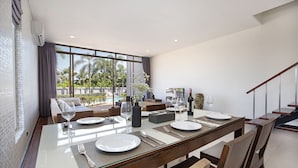 A modern dining area with a glass table set for four, surrounded by wooden chairs. - Spacious 3BR Pool Access Villa Argent 7 (Thep Krasattri)