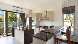 A modern kitchen with a central island, built-in appliances, and a view of the outdoors. - Spacious 3BR Pool Access Villa Argent 7 (Thep Krasattri)