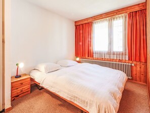 Cozy retreat with a single bed, nightstand, and window with curtains.