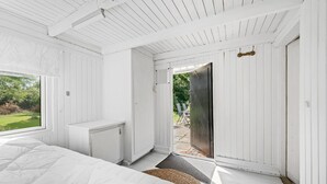 A bedroom with a bed, a radiator, a door leading outside, and a view of the garden. - 4 bedroom amazing home in Martofte (Martofte)