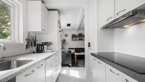 A modern kitchen with white cabinetry, stainless steel appliances, and a window providing natural light. - 4 bedroom amazing home in Martofte (Martofte)