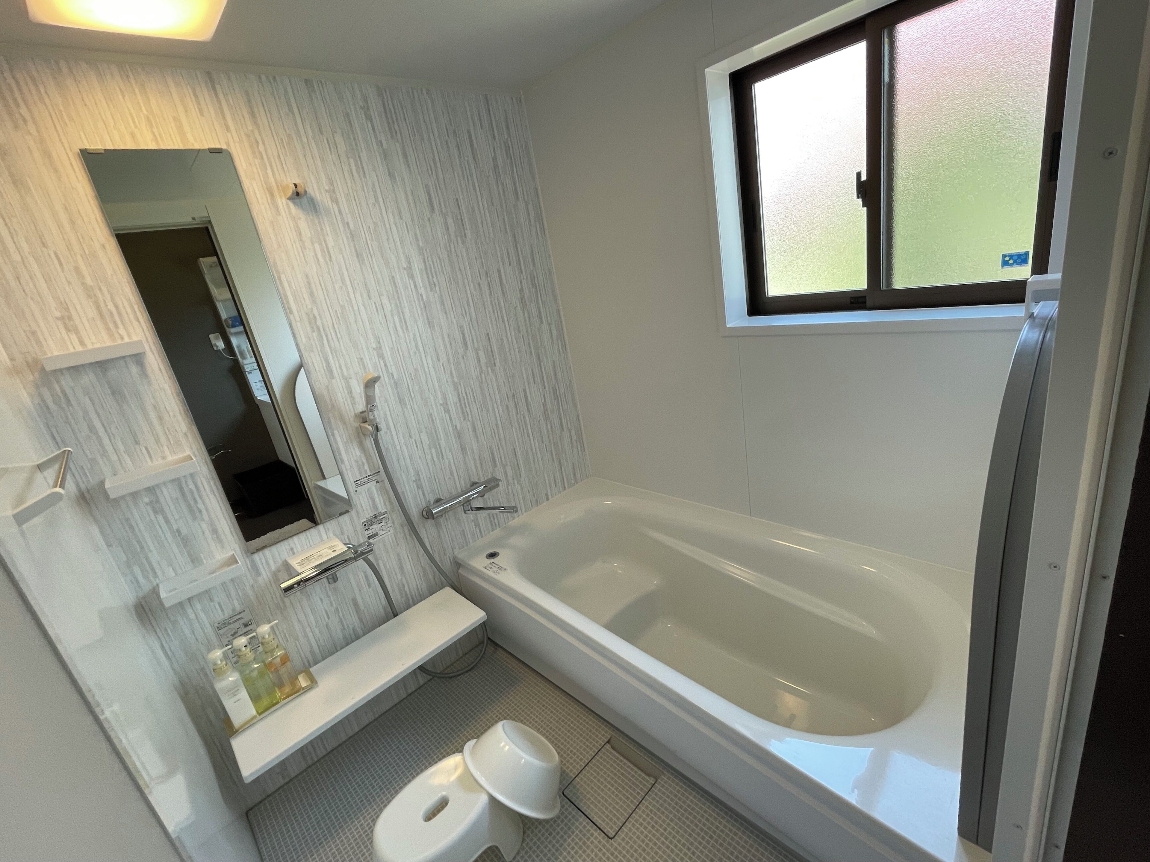 Une salle de bain avec une baignoire, des toilettes, un lavabo et une fenêtre.