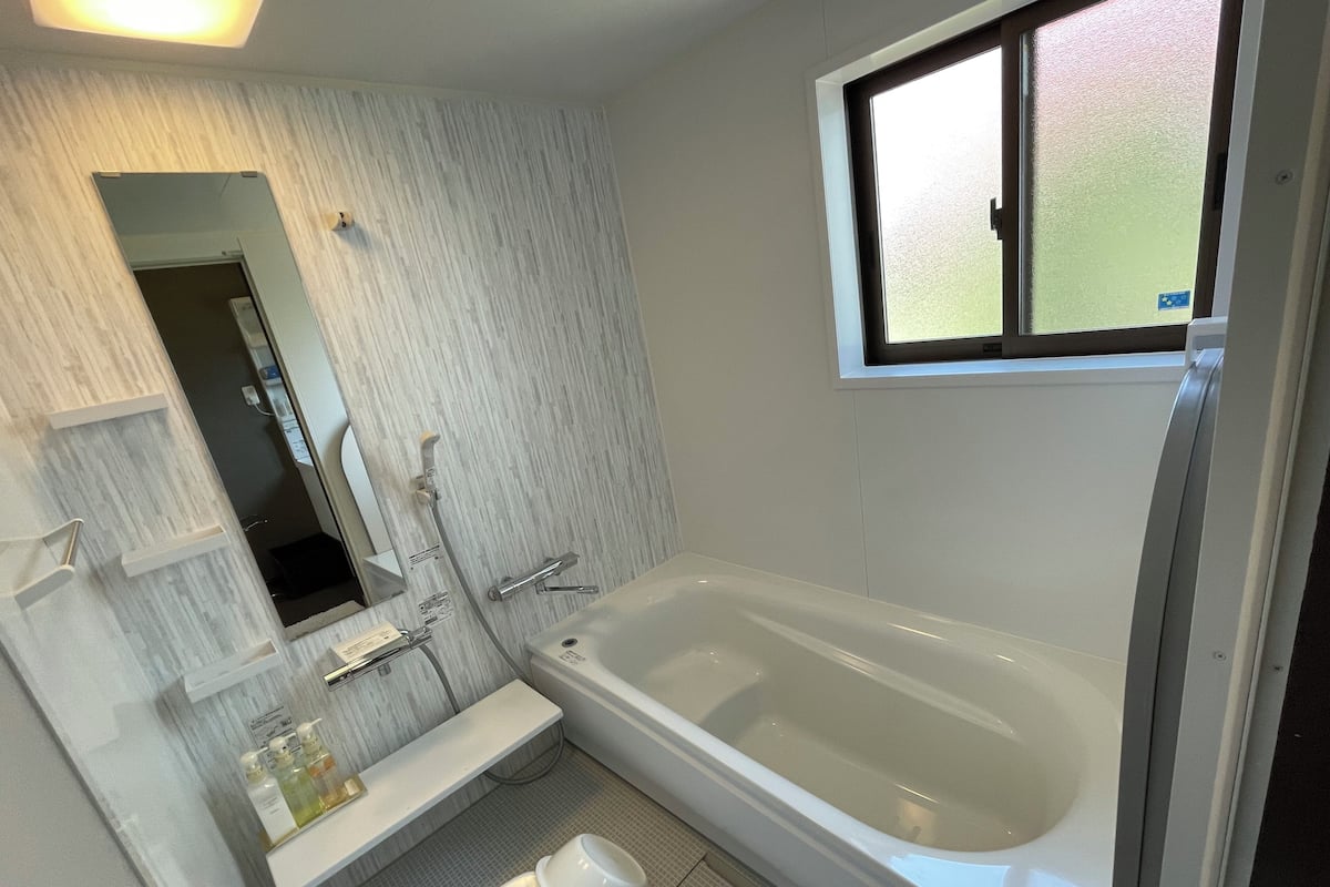Une salle de bain avec une baignoire, des toilettes, un lavabo et une fenêtre.