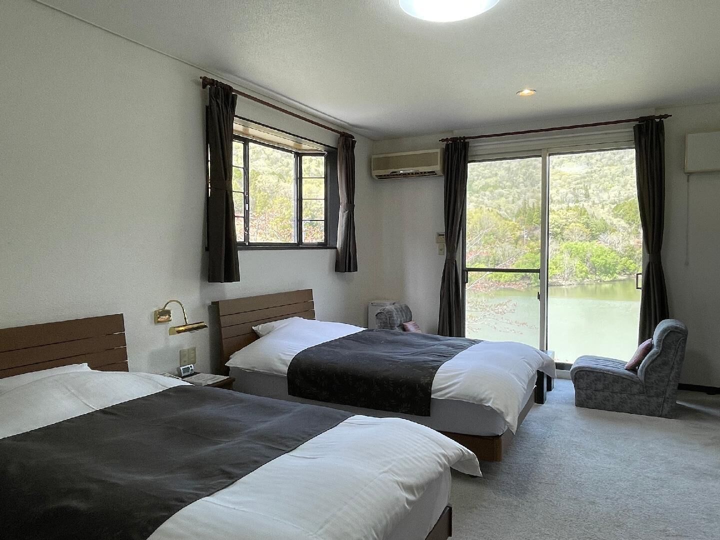 Une chambre d’hôtel avec deux lits, une chaise et une vue sur un lac.