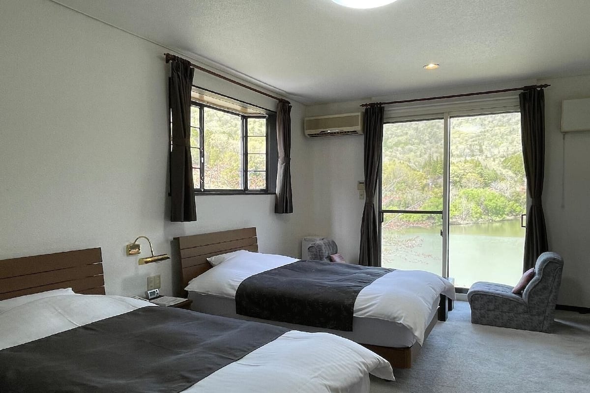 Une chambre d’hôtel avec deux lits, une chaise et une vue sur un lac.