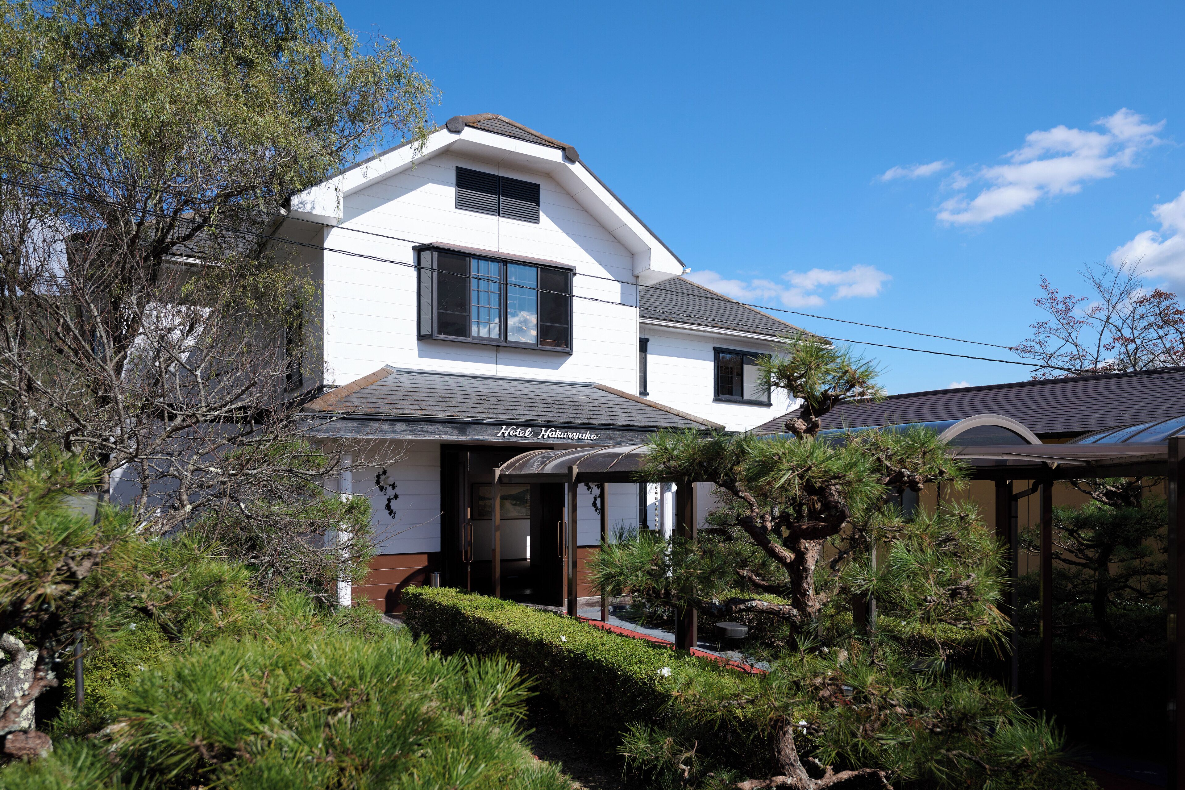 A two-story building with a covered entrance and a sign that reads "Hotel Higurashi."