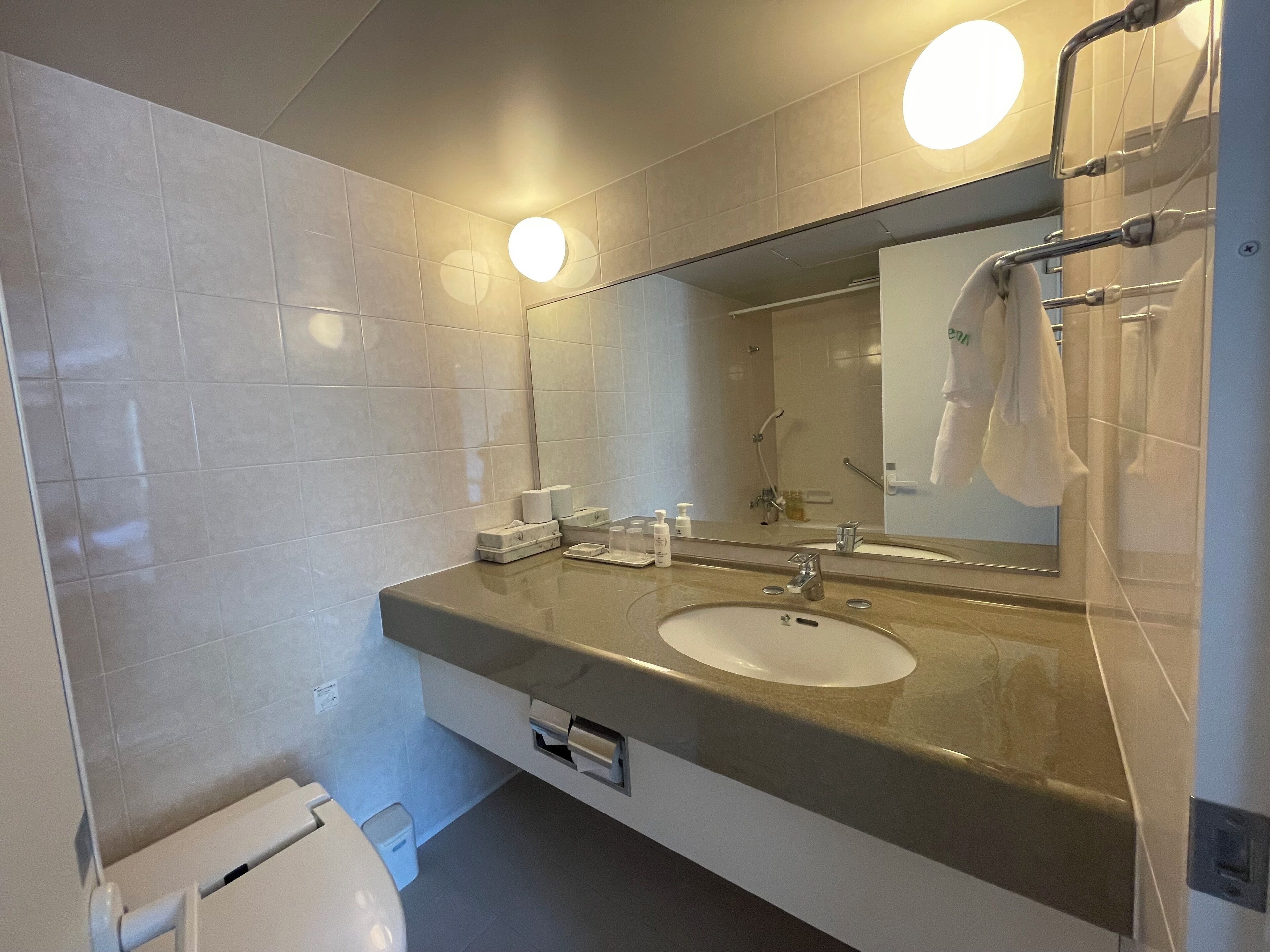 A modern bathroom with a large mirror, a sink, and a toilet.