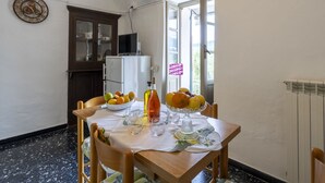 A dining area with a table set for two, a refrigerator, and a window with a view.
