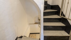 A staircase with a white wall and a black base, leading to a landing.