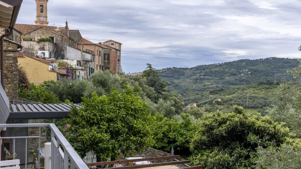 A hillside town with historic buildings, a prominent clock tower, and lush greenery.