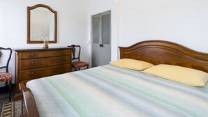 A bedroom with a wooden bed, a dresser, a mirror, and a door.