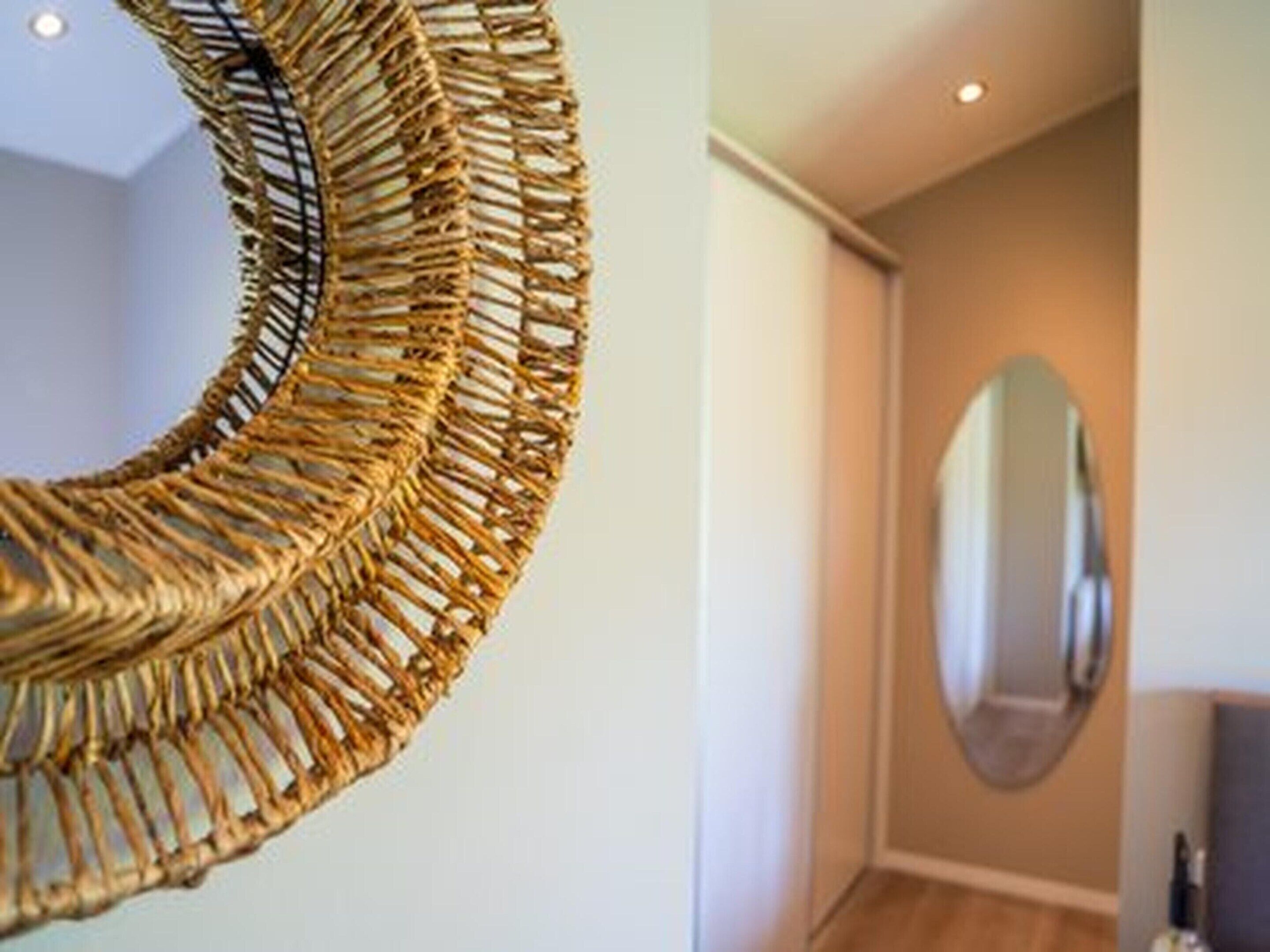 Un tapiz circular tejido en un pasillo con un espejo en la pared.