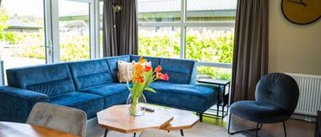 Una sala de estar moderna con un sofá azul, una mesa de comedor de madera y un jarrón de flores.