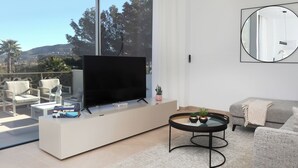 Un salon moderne doté d’un téléviseur à écran plat, de sièges confortables, d’une table basse et offrant une vue sur l’extérieur.