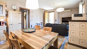 A modern kitchen with a wooden table, chairs, a clock, and a TV. - Stunning apartment in Albarè di Costermano with WiFi (Albarè di Costermano)