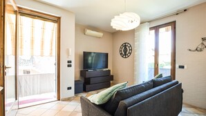 A living room with a sofa, a TV, and a wall clock. - Stunning apartment in Albarè di Costermano with WiFi (Albarè di Costermano)