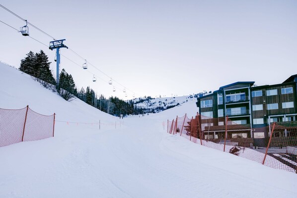 A ski slope with a chairlift, snow fences, and a building with multiple windows.