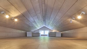 A spacious attic room with sloped wooden ceilings and a skylight.
