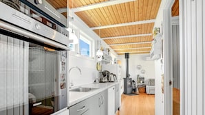 Une cuisine moderne avec des meubles blancs, un four encastré et un plafond en bois.