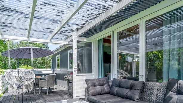 Une terrasse extérieure dotée d’un coin salon confortable, d’une table avec des magazines et d’un barbecue.