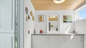 Une cuisine moderne avec des meubles blancs, un plafond en bois et une grande fenêtre.