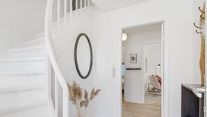 A staircase with a white railing, a wall-mounted oval mirror, and a vase with dried pampas grass. - "Ancel" - 1.5km to the fjord by Interhome (Tim)
