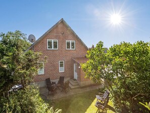 Stunning two-story home with a central entrance, flanked by windows, set amidst a beautifully manicured lawn and lush trees.