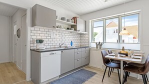 A modern kitchen with white cabinetry, a built-in oven, and a window overlooking a residential area. - "Ancel" - 1.5km to the fjord by Interhome (Tim)