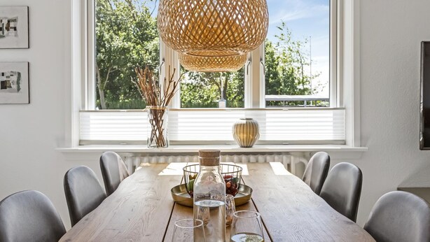 A dining area with a wooden table, chairs, a woven pendant light, and a window with a view of trees. - "Ancel" - 1.5km to the fjord by Interhome (Tim)
