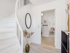 Staircase leads to an upper level, with a dining area featuring a modern chair and table below.