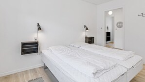 A modern bedroom with a large bed, bedside lamps, a small bedside table, and a white wall. - "Ancel" - 1.5km to the fjord by Interhome (Tim)